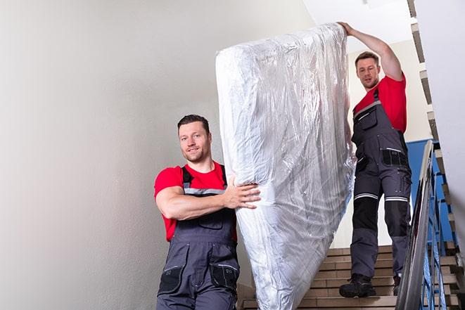 team of workers handling a box spring for disposal in Westville